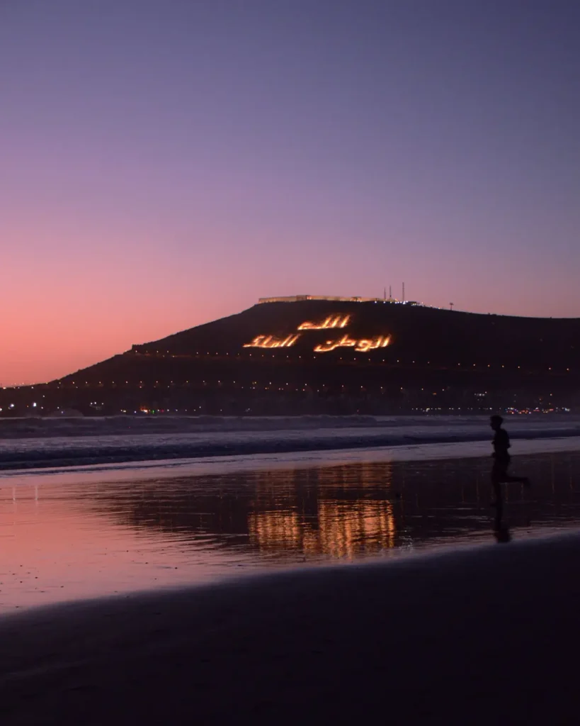 Sunset over Agadir beach with the illuminated Oufella hill inscription