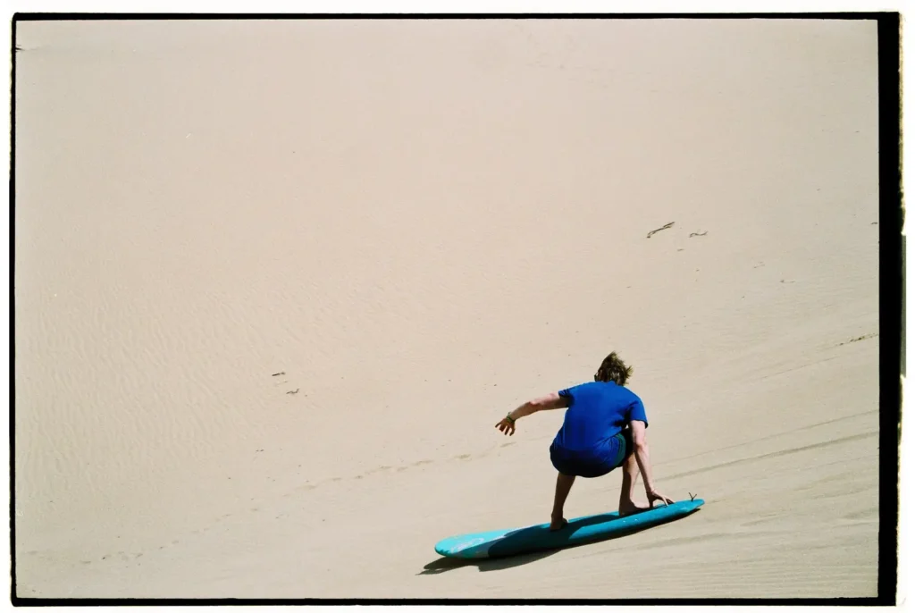 Sandboarder riding down a sand dune in Morocco