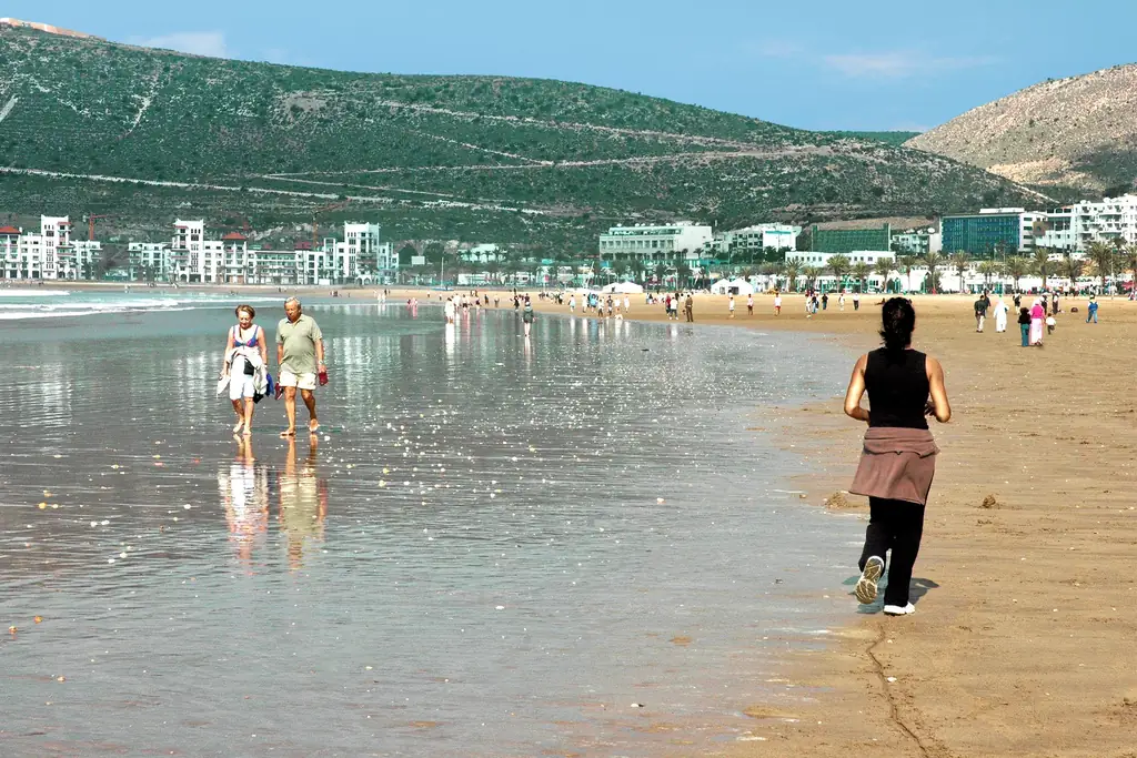 People walking on Agadir beach at low tide, a popular spot for outdoor photo shoots
