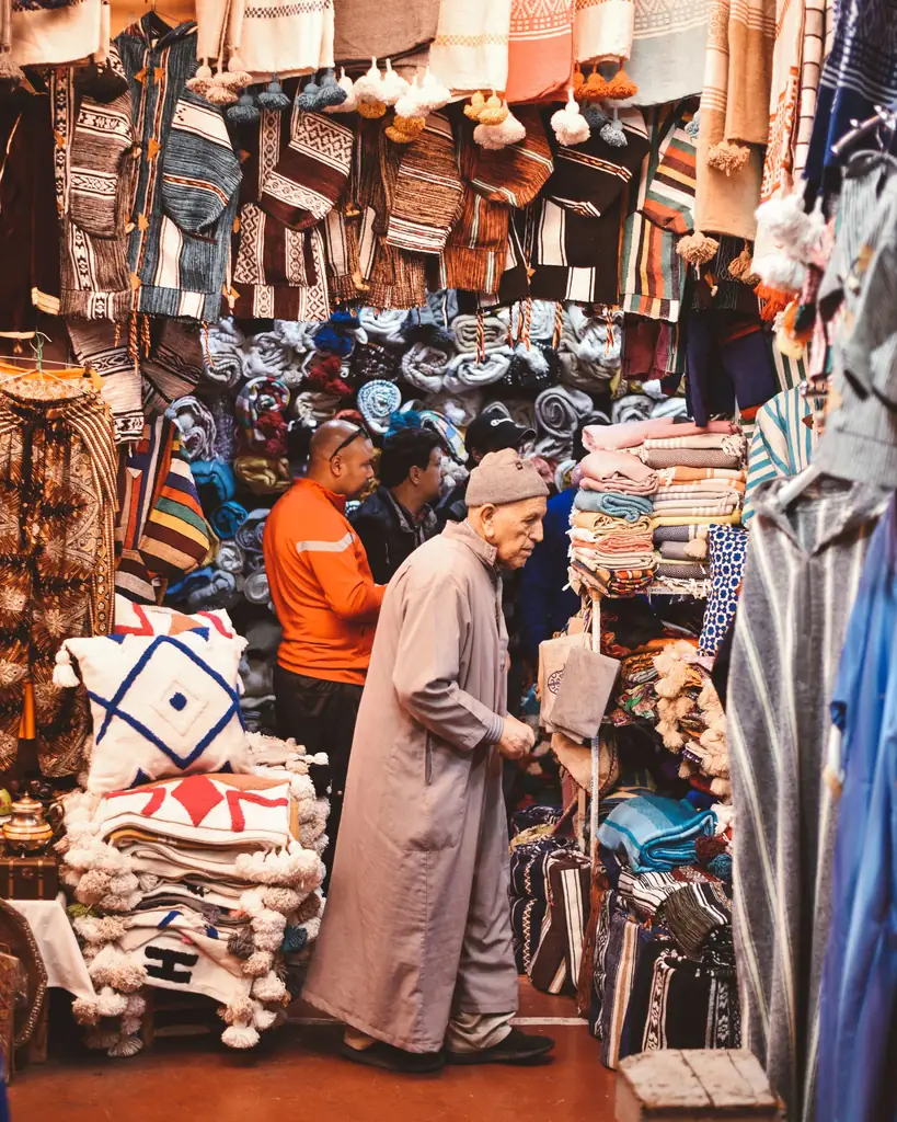 Shopkeeper among stacked rugs and cushions in an Agadir market shop