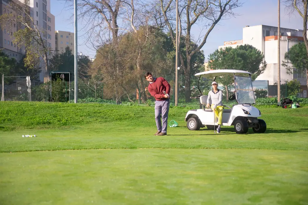 Golfer on the course with a golf cart nearby
