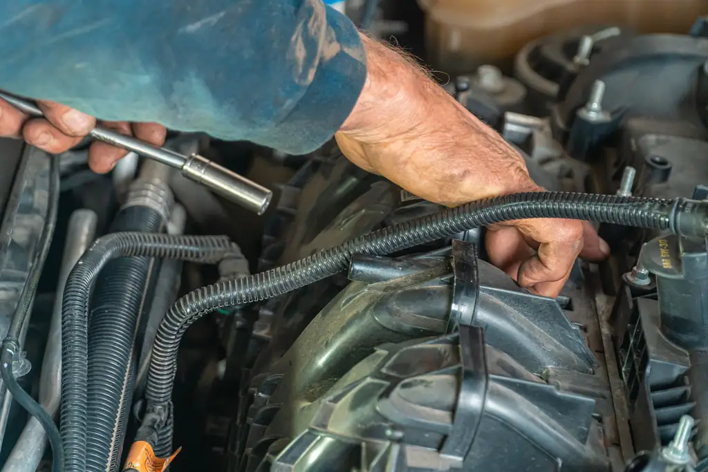 Hands of a mechanic checking engine hoses and components