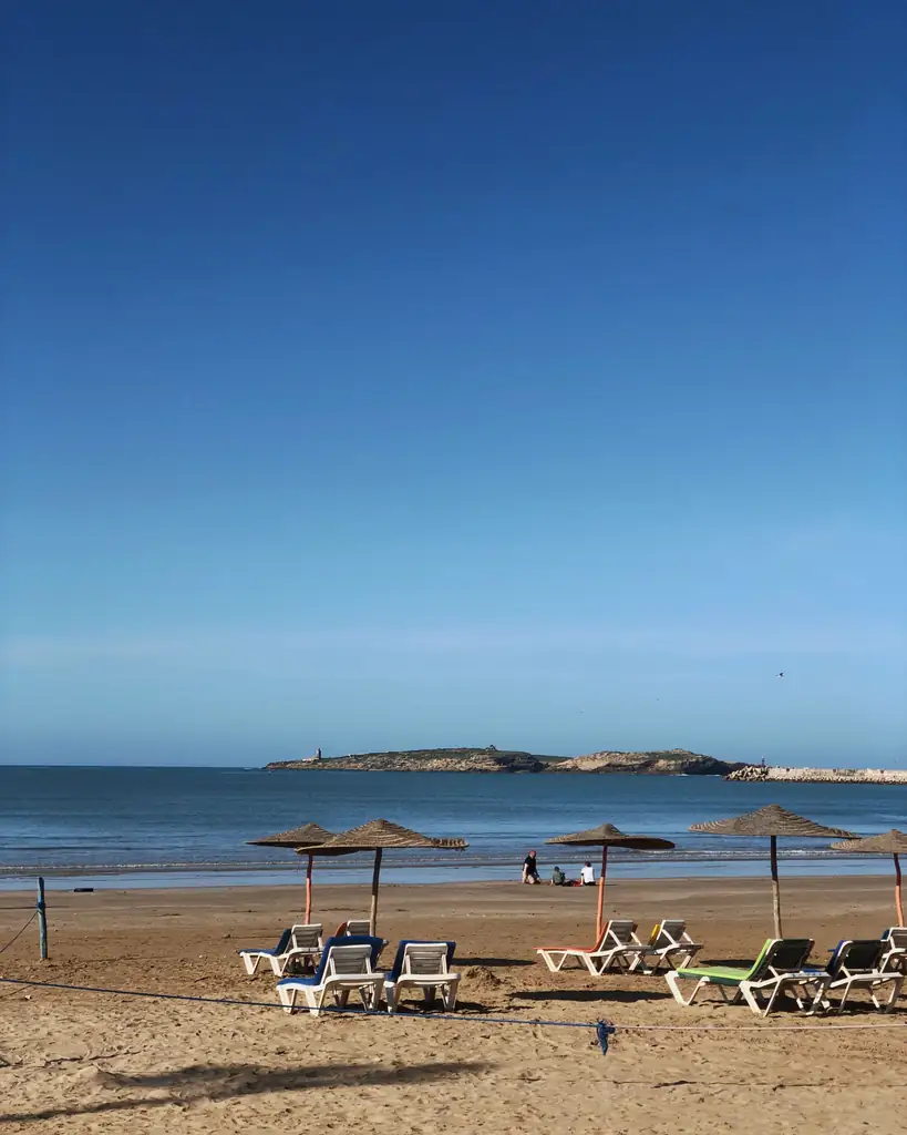 Sun loungers and parasols facing a calm sea on a Moroccan beach