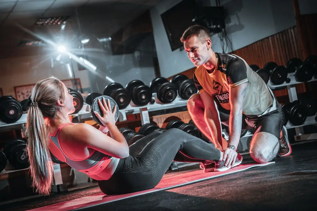 Personal trainer holding a client's feet during medicine ball sit-ups