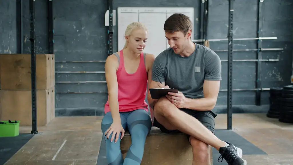 Personal trainer going over a workout plan with a client on a tablet