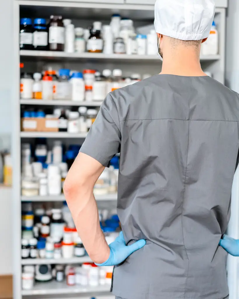 Pharmacist organizing medicine on pharmacy shelves