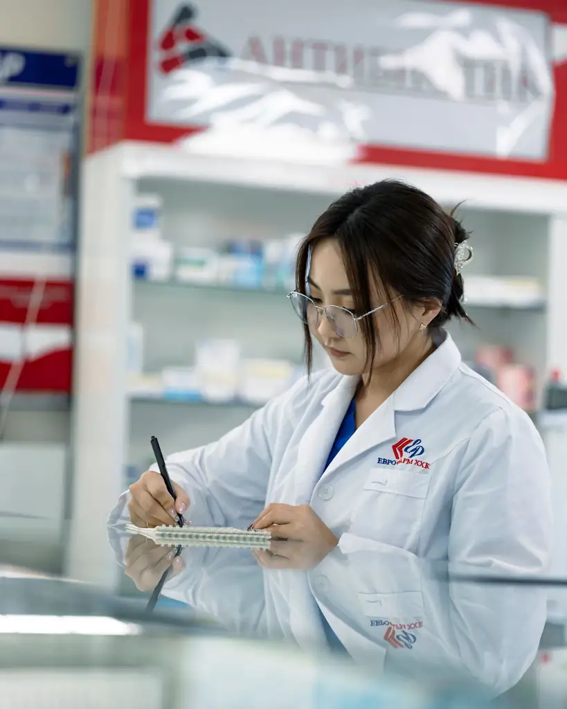 Pharmacist taking notes behind the pharmacy counter