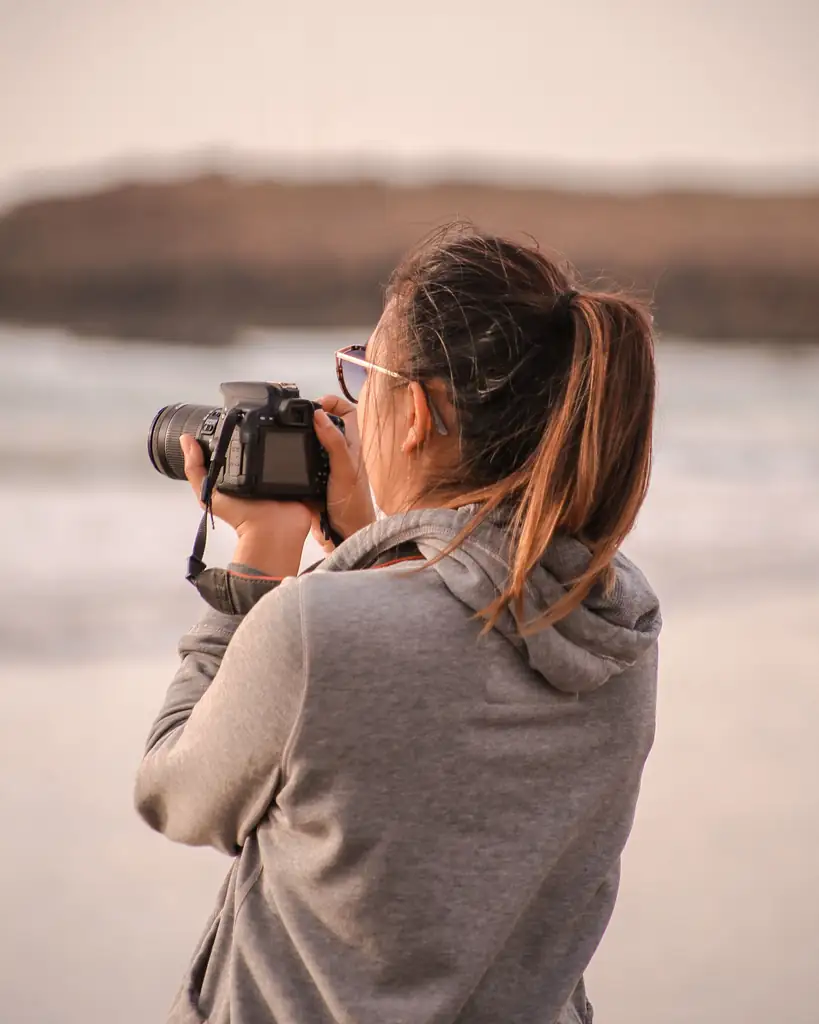 Photographer framing a beach scene with her camera