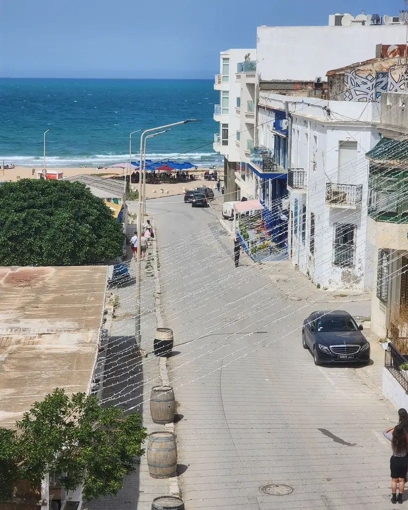 Parked cars along a seaside street with beach access in Morocco
