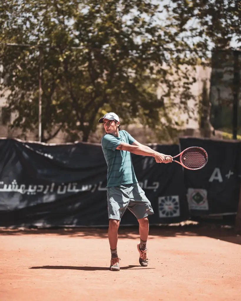 Tennis player swinging on an outdoor clay court